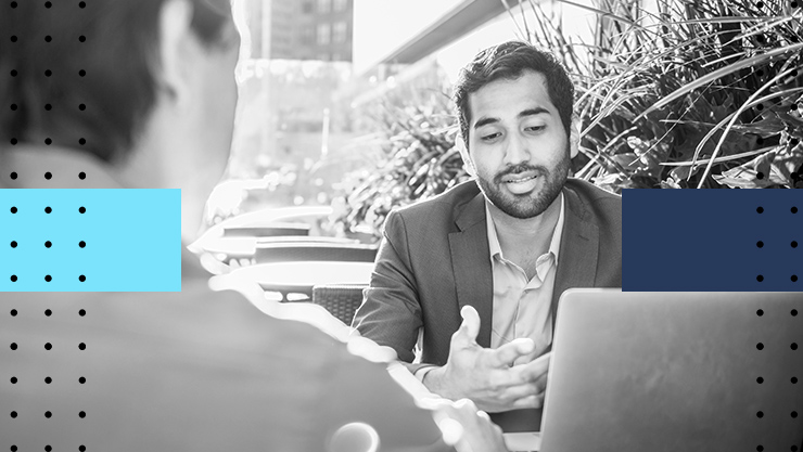 Two colleagues having a conversation in front of their laptops