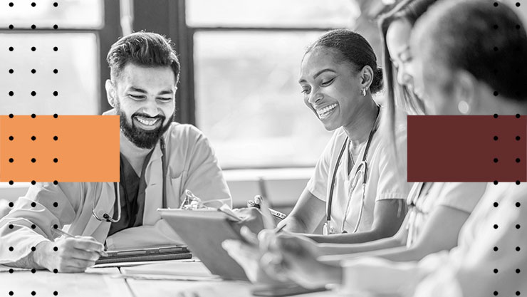 A group of medical professionals smiling and looking at a tablet