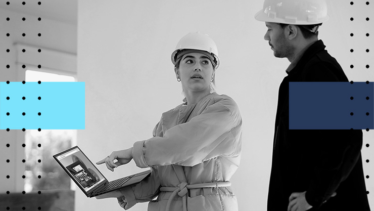 Two people in hardhats looking at a tablet
