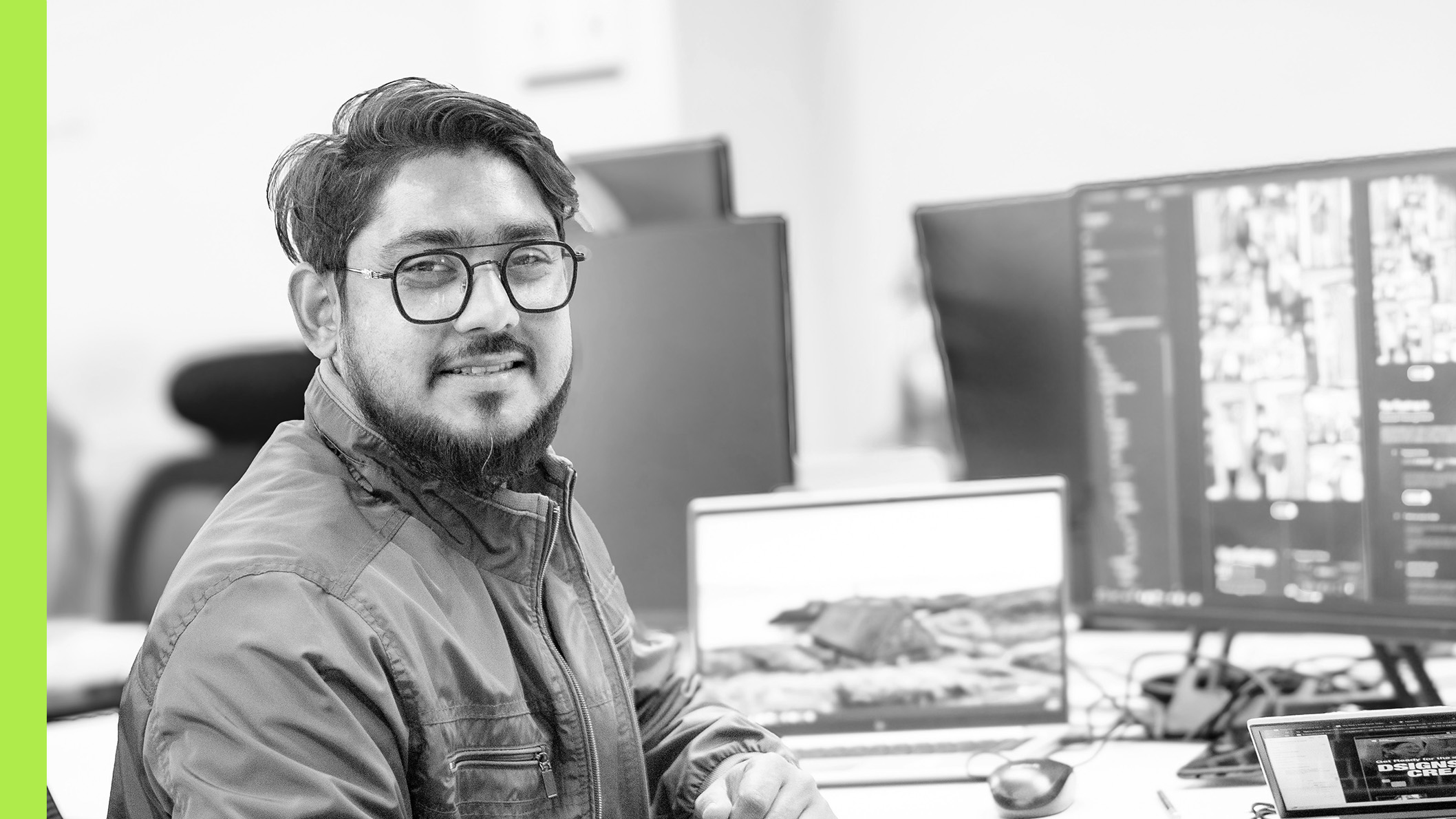 An individual at a laptop, looking at the camera with a smile.